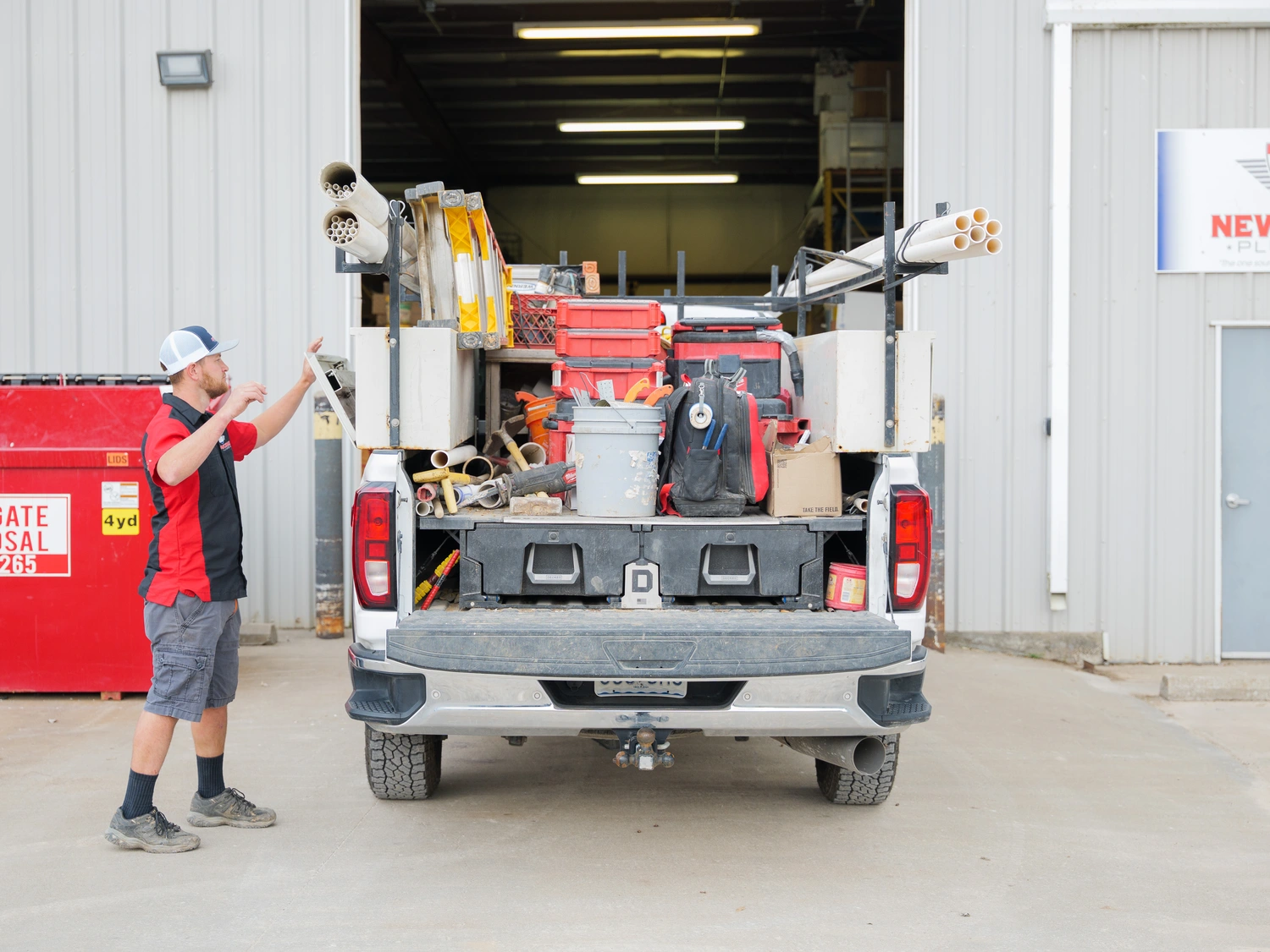 A man stands confidently in front of a large truck, showcasing a casual yet professional demeanor.